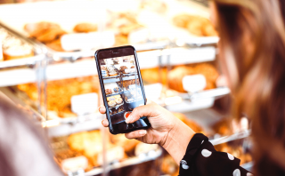 woman taking a photo of a donut case on her phone